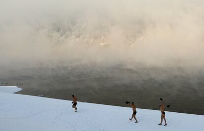 Varios entusiastas de la natación calientan en la orilla del río Yenisei antes del baño semanal, a una temperatura ambiental de 30 grados bajo cero, en la ciudad siberiana de Divnogorsk (Rusia).