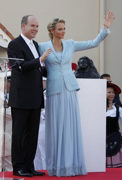 En el saludo de Alberto y Charlene de Mónaco a los monegascos congregados en la plaza se ha podido ver por primera vez de forma completo el diseño lucido por la princesa: un vestido largo, en un suave azul celeste, con puntilla en puños y bajos, cubierto por una chaqueta un poco más oscura del mismo color.