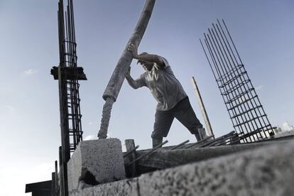 Un trabajador palestino vierte cemento en el techo de un edificio de apartamentos en construcci&oacute;n.