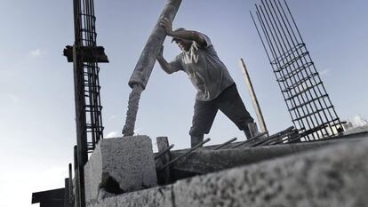 Um operário palestino derrama cimento no teto de um edifício.