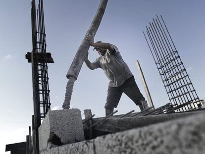 Un trabajador palestino vierte cemento en el techo de un edificio de apartamentos en construcci&oacute;n.