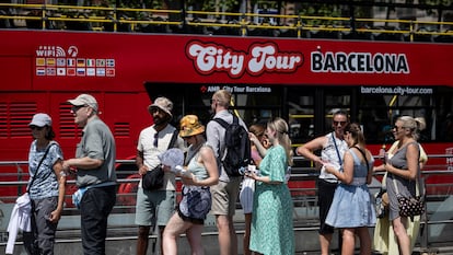 Turistas haciendo cola para subir a un autobús turístico en Barcelona.