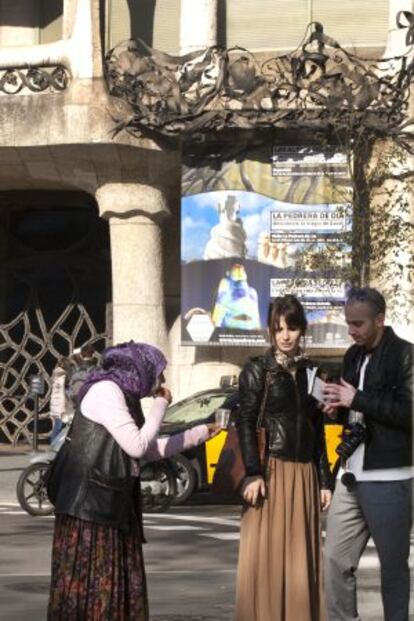 Una señora pide limosna a unos turistas en la puerta de la Pedrera.