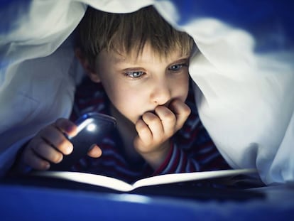 Menino lendo um livro iluminado pela luz do celular