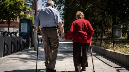 Dos ancianos caminan de la mano por la calle Caramuel, en el barrio de Puerta del Ángel, Madrid.