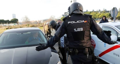 Efectivos de la Policía Nacional entre un vehículo de licencia VTC y un taxi a las puertas del recinto ferial de IFEMA.