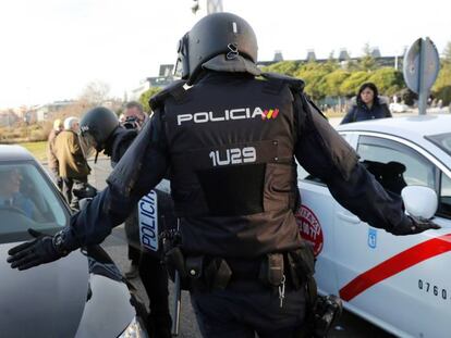 Efectivos de la Policía Nacional entre un vehículo de licencia VTC y un taxi a las puertas del recinto ferial de IFEMA.