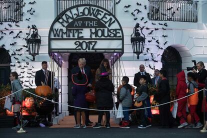 Los niños esperan su turno para recoger los caramelos que ofrecen el matrimonio Trump.