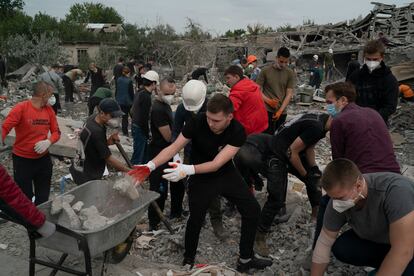 Voluntarios quitan escombros tras el bombardeo ruso a un bloque de viviendas en Zaporiyia, este domingo. 