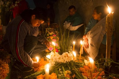 Grupos de familias velan a sus difuntos la madrugada del 2 de noviembre en el panteón de La Columna de la localidad de Tlacotepec, Puebla.