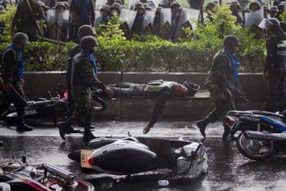 Unos militares transportan el cuerpo del compañero muerto en los enfrentamientos de ayer en las afueras de Bangkok.