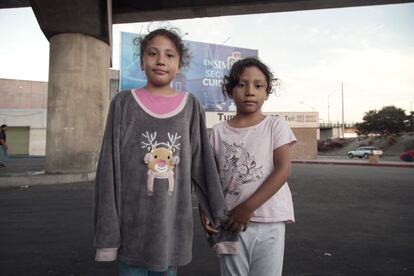 Dos hermanas hondureñas posan frente a la tienda de campaña donde duermen, a unos pocos metros del muro que separa Estados Unidos y México.