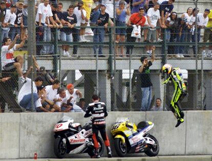 El italiano Valentino Rossi, derecha, salta la valla protectora, en presencia de Alex Barros, tras ganar la prueba de 500 cc del Gran Premio de Brasil, en el circuito de Jacarepagua, el 7 de octubre de 2000.