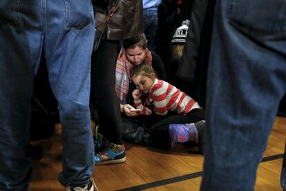 Madre e hija se sientan en el suelo mientras esperan la llegada de la candidata demócrata a la presidencia de Estados Unidos, Hillary Clinton, en un acto electoral en Manchester, New Hampshire, el 3 de febrero de 2016.