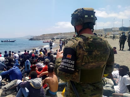 Un soldado del Ejército de Tierra observa a un grupo de inmigrantes que han logrado cruzar uno de los espigones fronterizos de Ceuta, este martes.