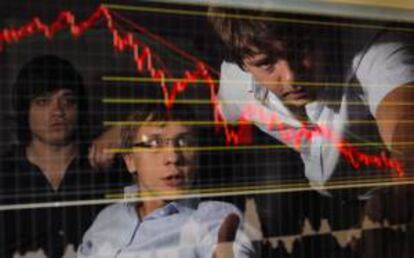 Empleados de una compañía de inversión en bolsa se muestran preocupados al contemplar un gráfico que detalla la tendencia a la baja de los valores bursátiles, en Moscú (Rusia). EFE/Archivo