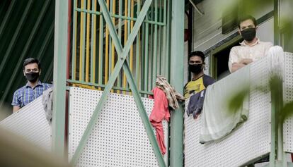 Varios trabajadores protegidos con mascarilla se asoman en un edificio de apartamentos humilde en Singapur, 28 de abril de 2020. La mayoría de los contagiados confirmados de coronavirus en esta ciudad-Estado son inmigrantes que viven en este tipo de edificios, generalmente hacinados y con condiciones higiénicas deficientes.