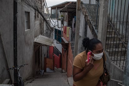 Uma mulher com uma máscara fala ao telefone em Paraisópolis, em São Paulo, no último 6 de maio.