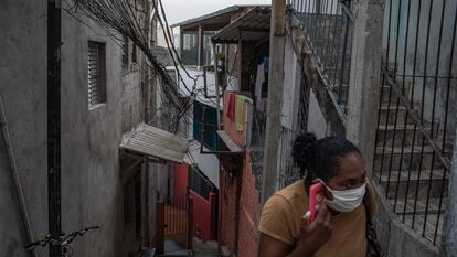 Uma mulher com uma máscara fala ao telefone em Paraisópolis, em São Paulo, no último 6 de maio.