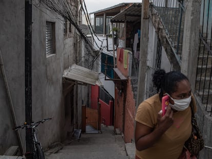 Uma mulher com uma máscara fala ao telefone em Paraisópolis, em São Paulo, no último 6 de maio.