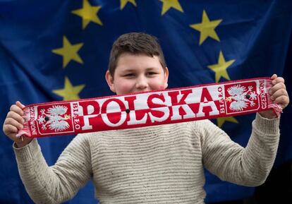 Un chico sosotiene una bufanda de Polonia con la bandera de la Unión Europea tras él, en una manifestación en la plaza del Parlamento en Londres como parte de un día nacional en apoyo de los migrantes en Reino Unido.