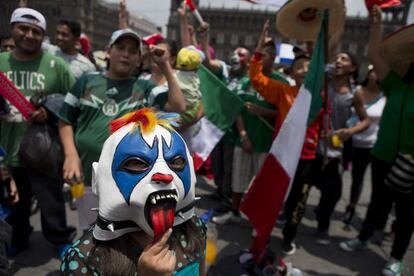 Una nña con una máscara de luchador mira el partido entre México y Brasil.