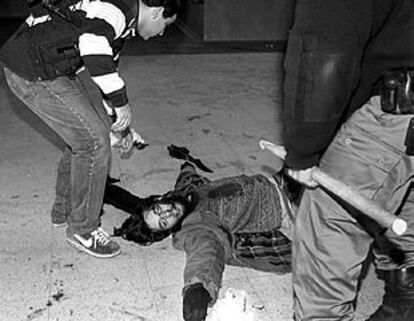 Un manifestante herido durante los disturbios de Buenos Aires yace en el suelo en presencia de dos policías.