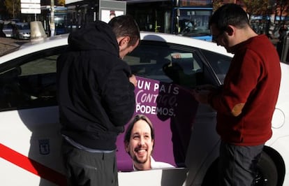 Dos taxista colocan publicidad electoral de Podemos en 2015.