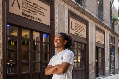 Eloín Lucas, uno de los camareros del restaurante La Pau, junto a las entradas que el local tiene en el pasaje de la Paz, en Barcelona. 