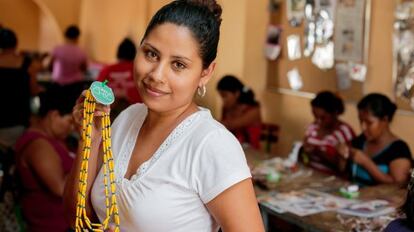 Una mujer muestra un diseño de Chureca en el taller donde se fabrica la bisutería.