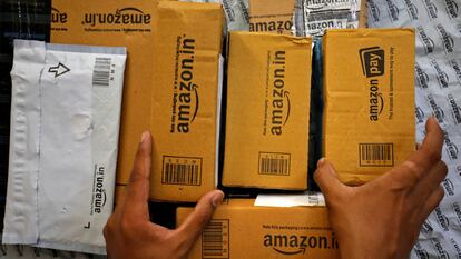 Un empleado selecciona paquetes en una furgoneta fuera de un almacén de Amazon.