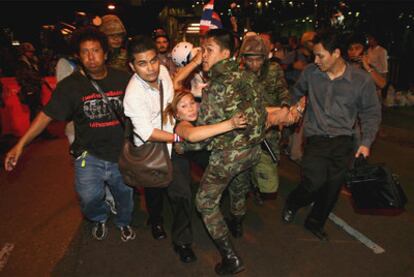 Una de las heridas en los ataques con granadas en Bangkok es trasladada por varias personas.