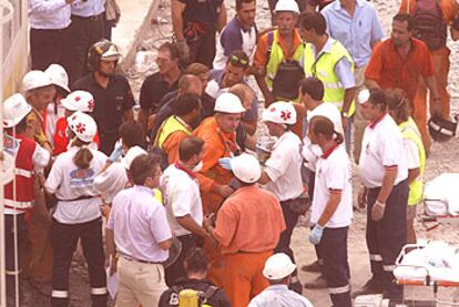 Miembros de los equipos de rescate atienden a los primeros obreros que lograron ser rescatados.