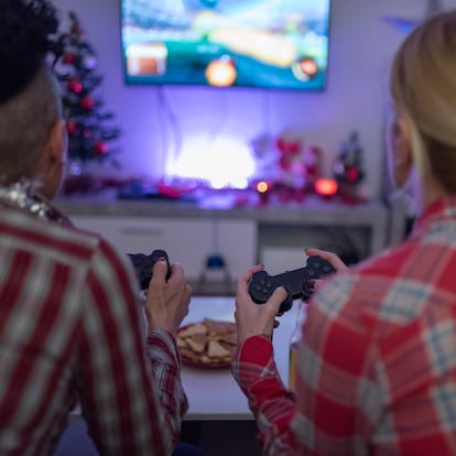 rear view of two women playing video game at home