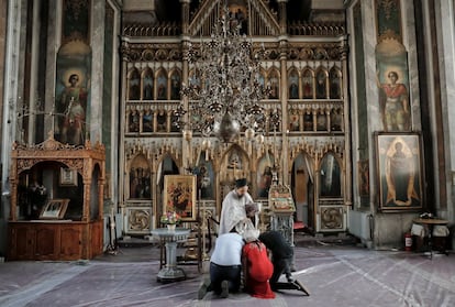 Varios miembros de la comunidad gitana se arrodillan mientras un sacerdote se prepara para leer oraciones.