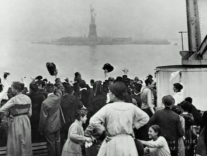 Inmigrantes llegan a Ellis Island a comienzos del siglo XX, con la Estatua de la Libertad al fondo.