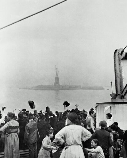 Inmigrantes llegan a Ellis Island a comienzos del siglo XX, con la Estatua de la Libertad al fondo.