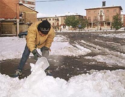 Un joven de la localidad de Saldaña (Palencia) retira la nieve junto a la plaza del Ayuntamiento, tras el temporal que ha azotado la provincia.