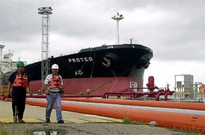 Dos trabajadores de compañía estatal PDVSA pasan delante de un petrolero anclado en el puerto de Maracaibo.