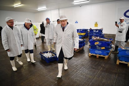 El primer ministro británico Boris Johnson tira de una caja llena de pescado, en su visita a una lonja de Grimsby (Reino Unido). 