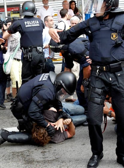 Un <i>mosso</i> inmoviliza en el suelo a un joven durante los incidentes en la plaza de Catalunya.