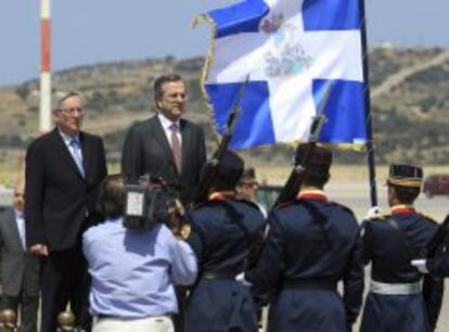 El primer ministro griego, Antonis Samaras (d), escucha el himno nacional junto a su homólogo de Luxemburgo, Jean-Claude Juncker (i), a su llegada al aeropuerto de Atenas (Grecia), ayer lunes 10 de junio de 2013.