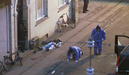 El cadàver del presumpte terrorista jeu en una vorera mentre dos forenses prenen mostres del lloc.