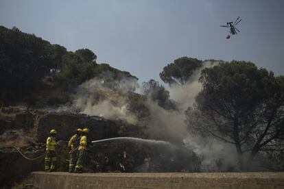 Miembros del Infoca intentan apagar el incendio con la ayuda de un helicóptero, en la localidad onubense de Nerva.