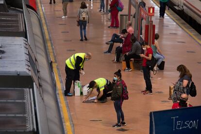 Los operarios colocan señales en los andenes para indicar la distancia de seguridad que los usuarios tienen que respetar, en la estación de Atocha (Madrid).