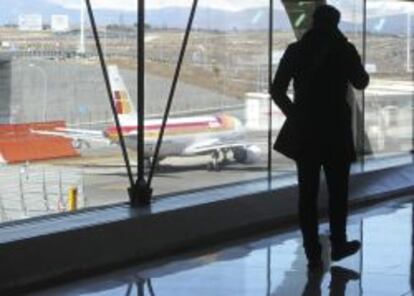 Un pasajero observa un avi&oacute;n de Iberia en el aeropuerto de Barajas en Madrid.