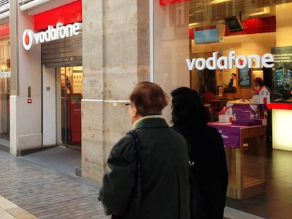 Varias personas pasan junto a una tienda Vodafone.