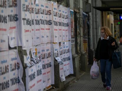 Una mujer camina frente a una pared cubierta con publicidad electoral en Buenos Aires.