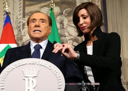 La senadora del partido Forza Italia, Anna Maria Bernini, coloca el micrófono para Silvio Berlusconi cuando llega para hablar con los medios durante el segundo día de consultas con el presidente italiano Sergio Mattarella en el Palacio del Quirinal en Roma (Italia).