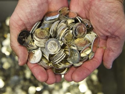 Un hombre sostiene varias monedas de euro.